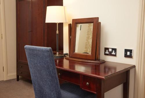 a desk with a mirror and a chair in a room at The Bell Hotel Woburn By Greene King Inns in Woburn