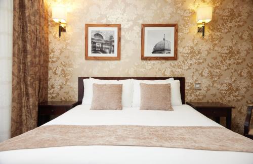 1 dormitorio con 1 cama blanca y 2 cuadros en la pared en The Bell Hotel Woburn By Greene King Inns en Woburn