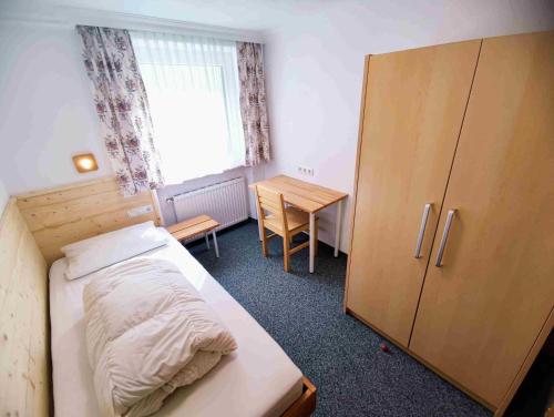 ザンクト・レオンハルト・イム・ピッツタールにあるGruppotel Alte Postのベッドルーム1室(ベッド1台付)、木製キャビネットが備わります。