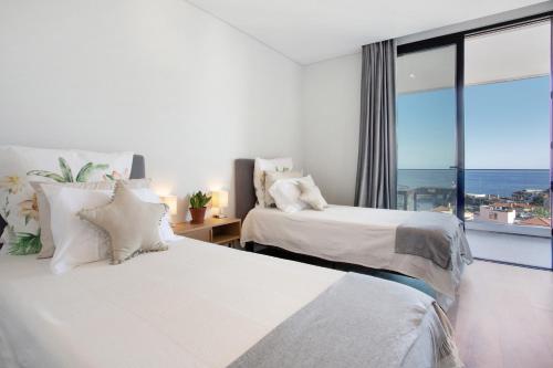 two beds in a bedroom with a view of the ocean at Casa Castanheta in Câmara de Lobos