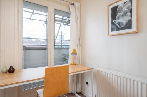 ein Heimbüro mit einem Schreibtisch und einem Fenster in der Unterkunft The Aristocrat - Fitzrovia - by Frankie Says in London
