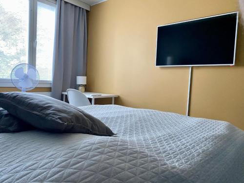 1 dormitorio con 1 cama y TV de pantalla plana en la pared en Huttu - Ihqu kaksio mahtavalla sijainnilla, en Iisalmi