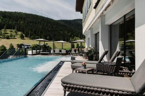 a swimming pool with lounge chairs next to a building at Hotel Neubergerhof in Filzmoos