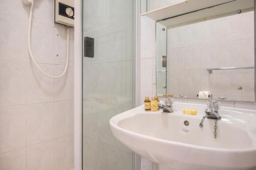 ein weißes Badezimmer mit einem Waschbecken und einem Spiegel in der Unterkunft The Aristocrat - Fitzrovia - by Frankie Says in London