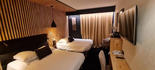 um quarto de hotel com duas camas e uma televisão em Hôtel Les Brises em La Rochelle