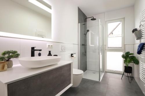 ein weißes Badezimmer mit Waschbecken und Dusche in der Unterkunft Appartementhaus kleines Glück &MeineCardPLUS in Willingen