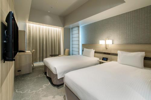 a hotel room with two beds and a flat screen tv at Hotel Keihan Tsukiji Ginza Grande in Tokyo