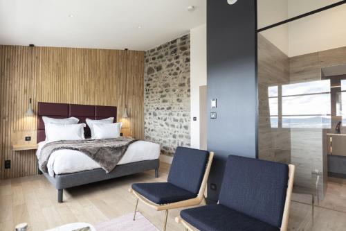 a bedroom with a bed and two chairs at Hôtel Origines par Adrien Descouls in Issoire