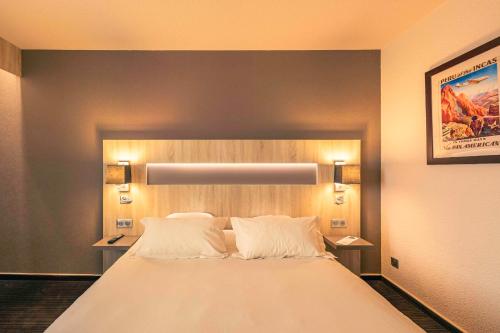 een slaapkamer met een groot wit bed met 2 kussens bij Best Western Marseille Aeroport in Vitrolles