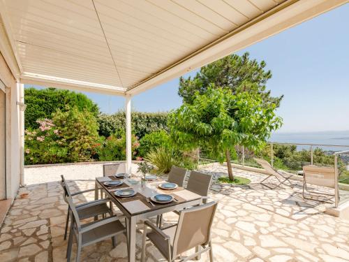 a table and chairs on a patio with a view of the ocean at Villa Clos Romain by Interhome in Les Issambres