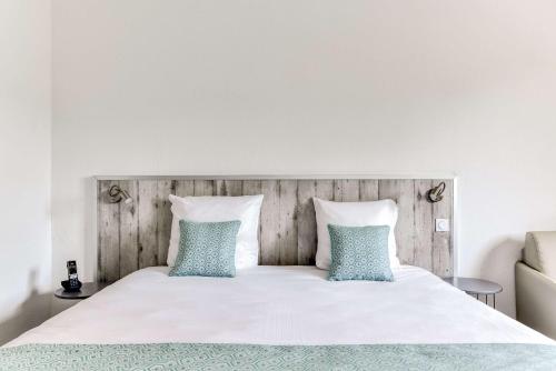 a bedroom with a white bed with two blue pillows at Sure Hotel by Best Western Beziers Le Monestie in Béziers
