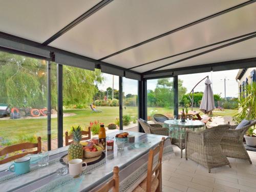 un patio avec une table, des chaises et des fenêtres dans l'établissement Holiday Home La Roseraie by Interhome, à Kerbors