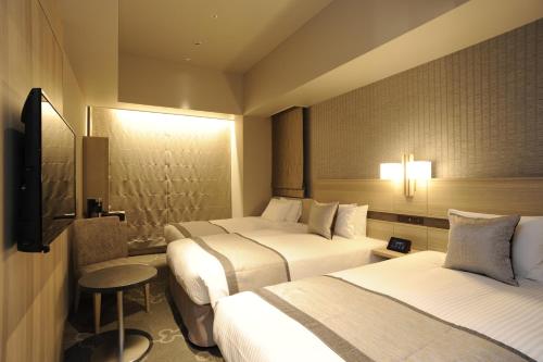 a hotel room with two beds and a television at Hotel Keihan Tsukiji Ginza Grande in Tokyo