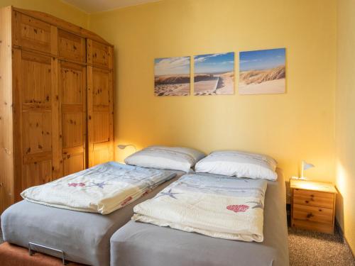 twee aparte bedden in een slaapkamer met twee foto's aan de muur bij Apartment Am Strom-3 by Interhome in Ummanz