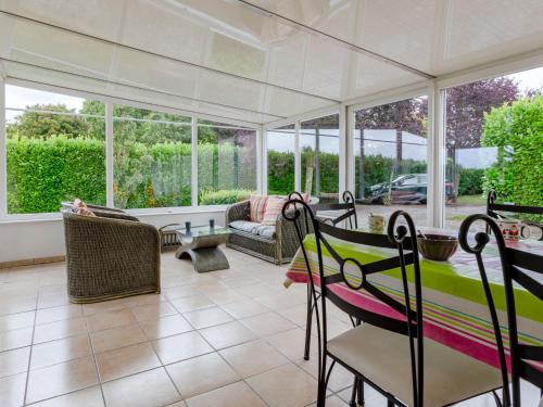 einen Wintergarten mit einem Tisch, Stühlen und Fenstern in der Unterkunft Holiday Home Le Saint Vigor - BAX400 by Interhome in Saint-Vigor-le-Grand