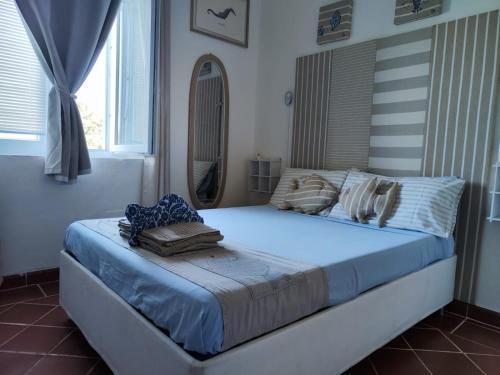 una camera da letto con un letto con lenzuola blu e uno specchio di Pino Marino a San Felice Circeo