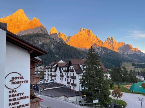 ein Hotel mit Bergen im Hintergrund und ein Gebäude in der Unterkunft Hotel Cima Rosetta - BW Signature Collection in San Martino di Castrozza