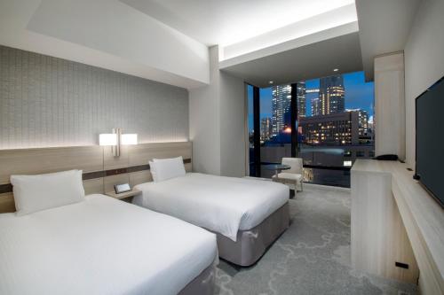 a hotel room with two beds and a view of a city at Hotel Keihan Tsukiji Ginza Grande in Tokyo