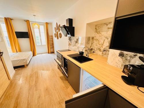 une cuisine avec un plan de travail, un évier et une télévision dans l'établissement Les Appartements de Nana 4 - Studio hypercentre, Rue Meynadier, Palais & Plage, clim, wifi, à Cannes