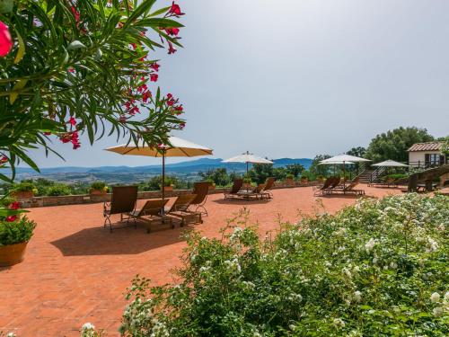 a group of chairs and umbrellas on a brick patio at Apartment Santa Marta by Interhome in Cinigiano