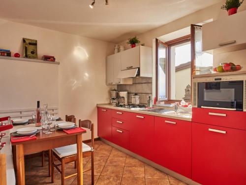 a kitchen with red cabinets and a table in it at Holiday Home Rustico Simona - GRV255 by Interhome in Gravedona
