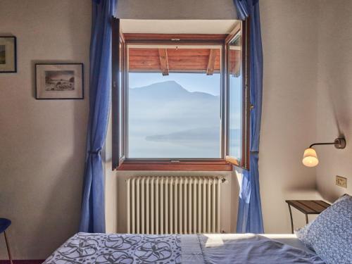 a bedroom with a window with blue curtains and a radiator at Holiday Home Rustico Simona - GRV255 by Interhome in Gravedona