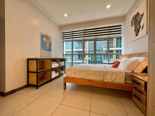 a bedroom with a bed and a large window at Skynest - urban luxury apartments by El Mufasa in Nairobi