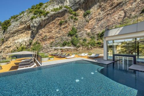 a villa with a swimming pool in front of a mountain at Gardea SoulFamily Resort in Nago-Torbole