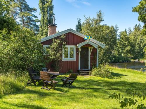 a small red house with benches in the grass at Holiday Home Lidelund by Interhome in Tingsryd