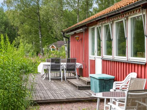 a red cabin with a table and chairs on a deck at Holiday Home Gapern - VMD044 by Interhome in Killstad