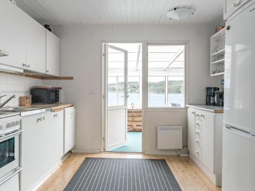 une cuisine avec des placards blancs et une grande fenêtre dans l'établissement Chalet Uskeboda - VML215 by Interhome, à Nora