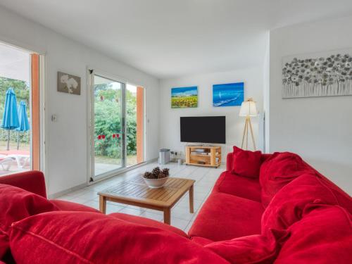 un salon avec un canapé rouge et une télévision dans l'établissement Holiday Home Les Acacias by Interhome, à Vendays-Montalivet