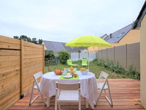 stół i krzesła z żółtym parasolem na tarasie w obiekcie Holiday Home La Criée by Interhome w mieście La Turballe
