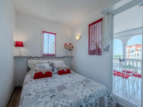 a bedroom with a bed with red pillows and a window at Apartment Pointe Vermeille-5 by Interhome in Le Barcarès