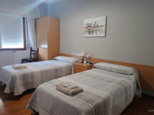 a room with two beds with towels on them at Albergue Camiño Real in Sigüeiro