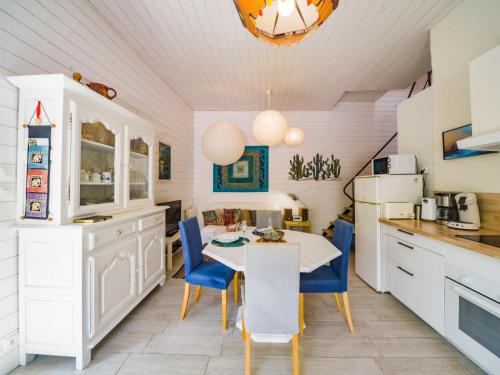 uma cozinha com armários brancos e uma mesa e cadeiras em Holiday Home La petite maison blanche by Interhome em Chissay-en-Touraine