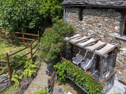 a garden with two chairs and flowers next to a building at Chalet Il Gianlupo by Interhome in Bognanco