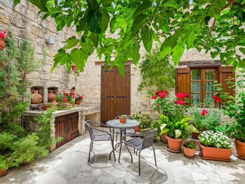 un patio con mesa, sillas y plantas en Sanders Arsorama, en Arsos