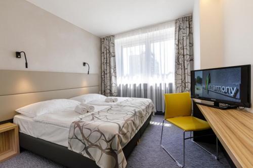 オストラヴァにあるHarmony Club Hotelのベッド1台、薄型テレビが備わるホテルルームです。
