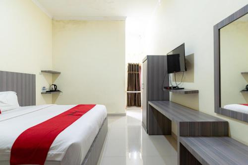 SinabonoにあるRedDoorz At Pariban Homestay Parbabaのベッドとテレビが備わるホテルルームです。