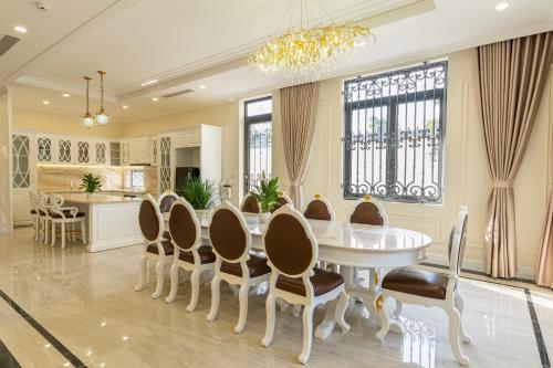 una sala da pranzo con tavolo e sedie bianchi di VILLA PARK a Kinh Dinh