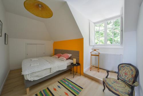 1 dormitorio con 1 cama, 1 silla y 1 ventana en La Genêtière - Grande maison avec étang en Sologne en Méry-ès-Bois