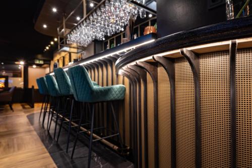 a row of green chairs sitting in a bar at Hotel Bom in Burgh Haamstede