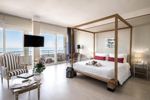 a bedroom with a canopy bed and a living room at Hotel Sina Astor in Viareggio