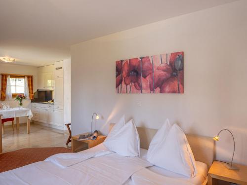 ein Schlafzimmer mit einem Bett mit weißer Bettwäsche und einem Gemälde an der Wand in der Unterkunft Apartment Allegra Sur 201 by Interhome in Zuoz