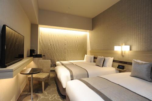 a hotel room with two beds and a flat screen tv at Hotel Keihan Tsukiji Ginza Grande in Tokyo