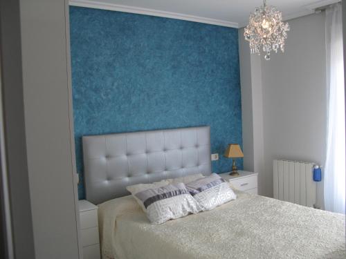 1 dormitorio con 1 cama con pared azul en Suances Costa Quebrada, en Suances