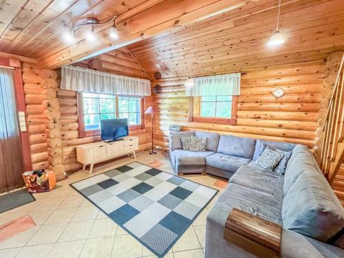 - un salon avec un canapé et une télévision dans une cabane en rondins dans l'établissement Holiday Home Kaakonranta by Interhome, à Kinnula