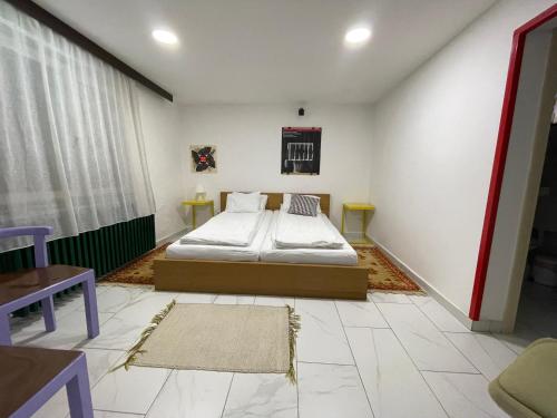 - une chambre avec un lit, deux tables et une fenêtre dans l'établissement PB Garden Apartman, à Sremska Mitrovica