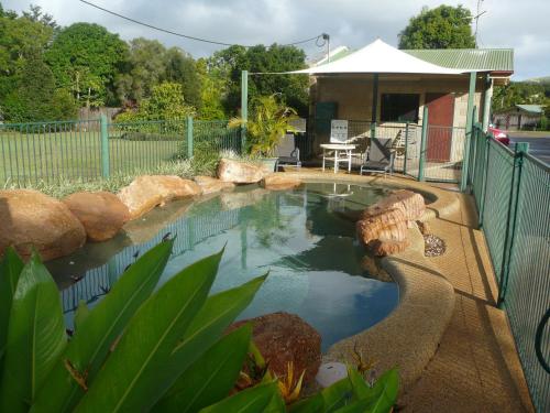 a swimming pool in a yard next to a house at Curtain Fig Motel in Yungaburra
